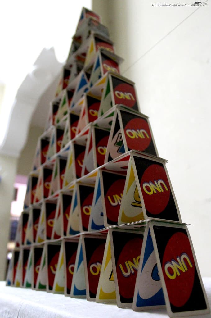 Image of people playing UNO at a vibrant social club event, with colorful cards and a DJ booth in the background.